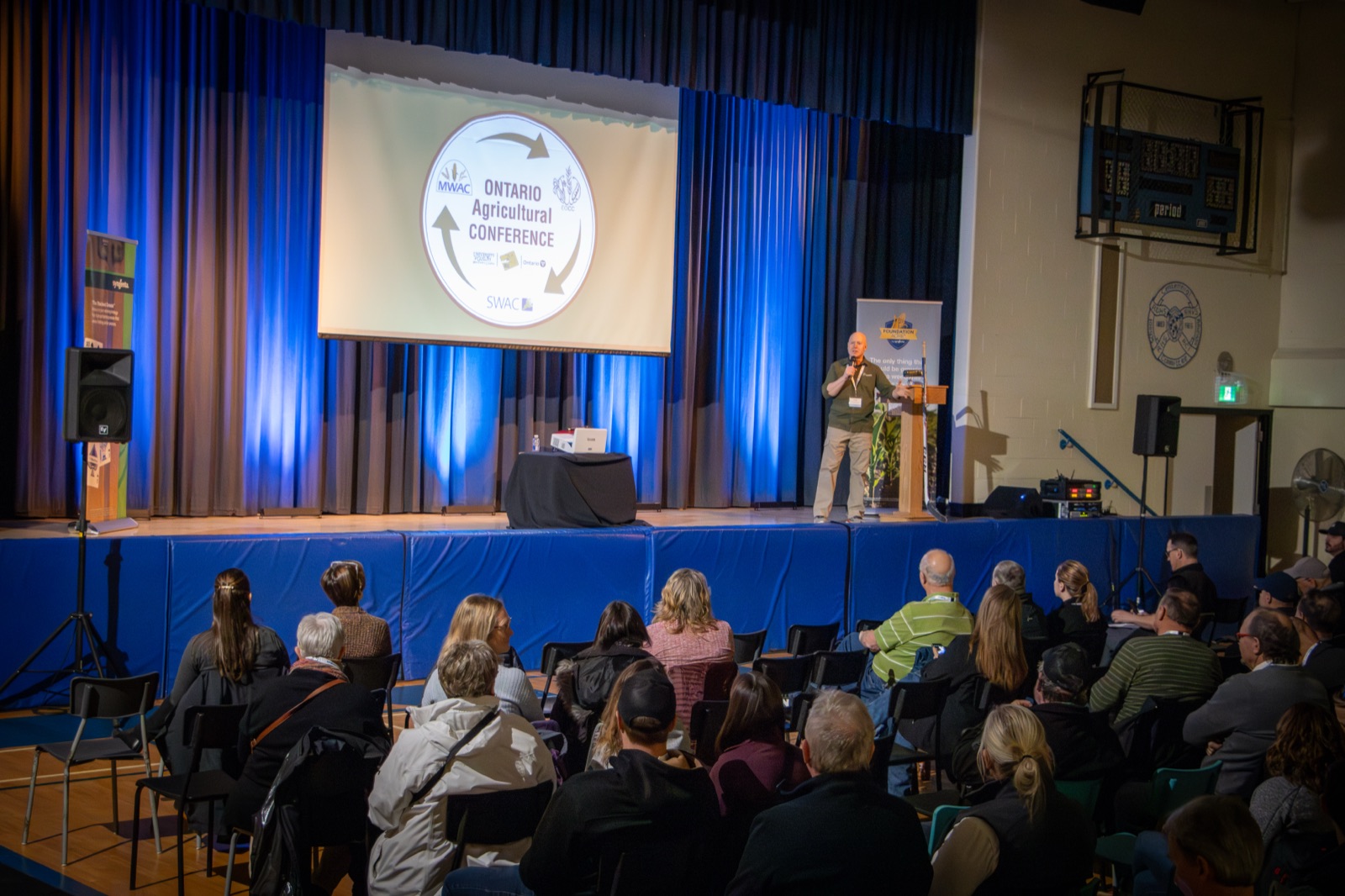 An audience listening to a speaker beneath the OAgC conference logo
